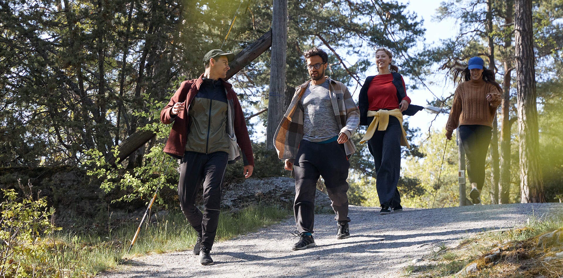 Nyproduktion Salem - foto på fyra personer går på en grusväg i skogen. De bär avslappnade kläder och verkar njuta av en solig dag utomhus.