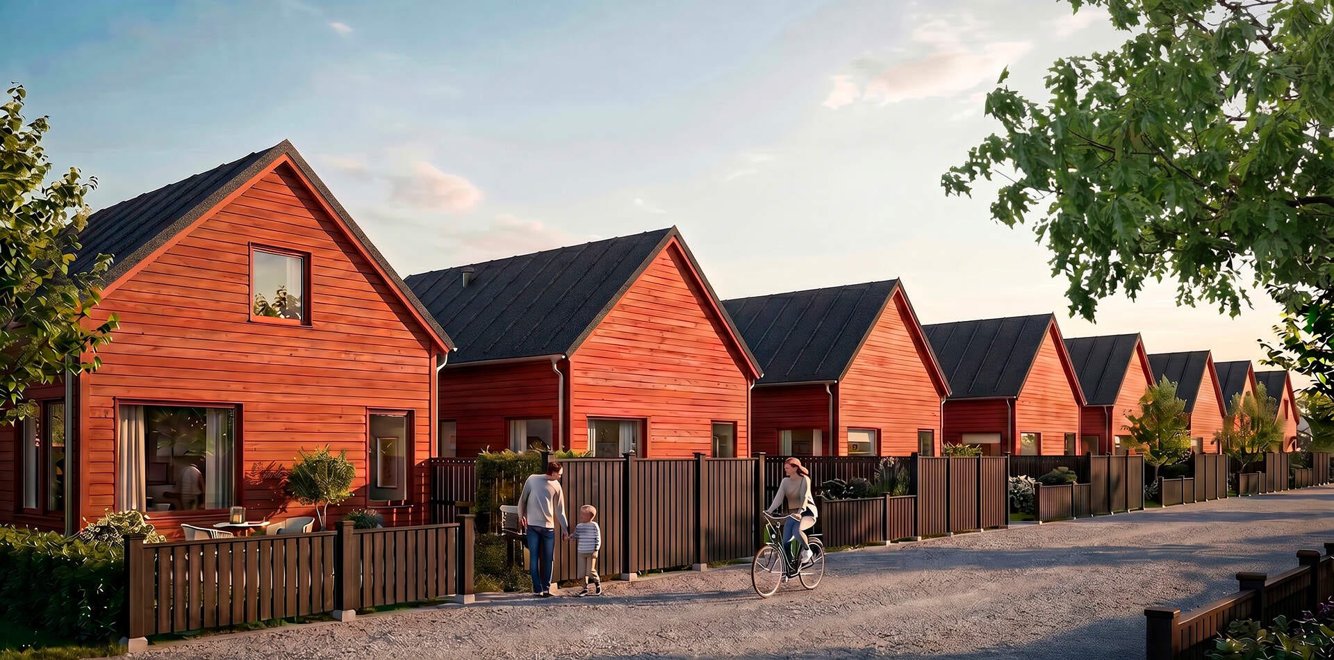 Visualisering - Nyproduktion i Ekängen - Rad med röda trähus med svarta tak längs grusväg, inhägnade uteplatser och personer som promenerar och cyklar.