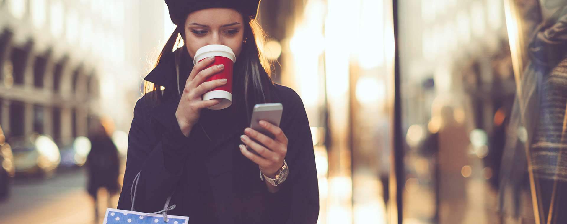 Kvinna som dricker kaffe och kollar telefonen